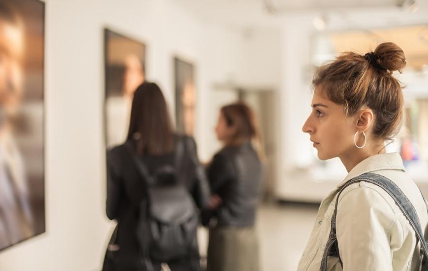 A young woman looks at a painting in an art museum